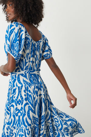 The model is wearing a Velvet by Graham & Spencer MADILYN PRINTED COTTON GAUZE MIDI DRESS with a splashy print.