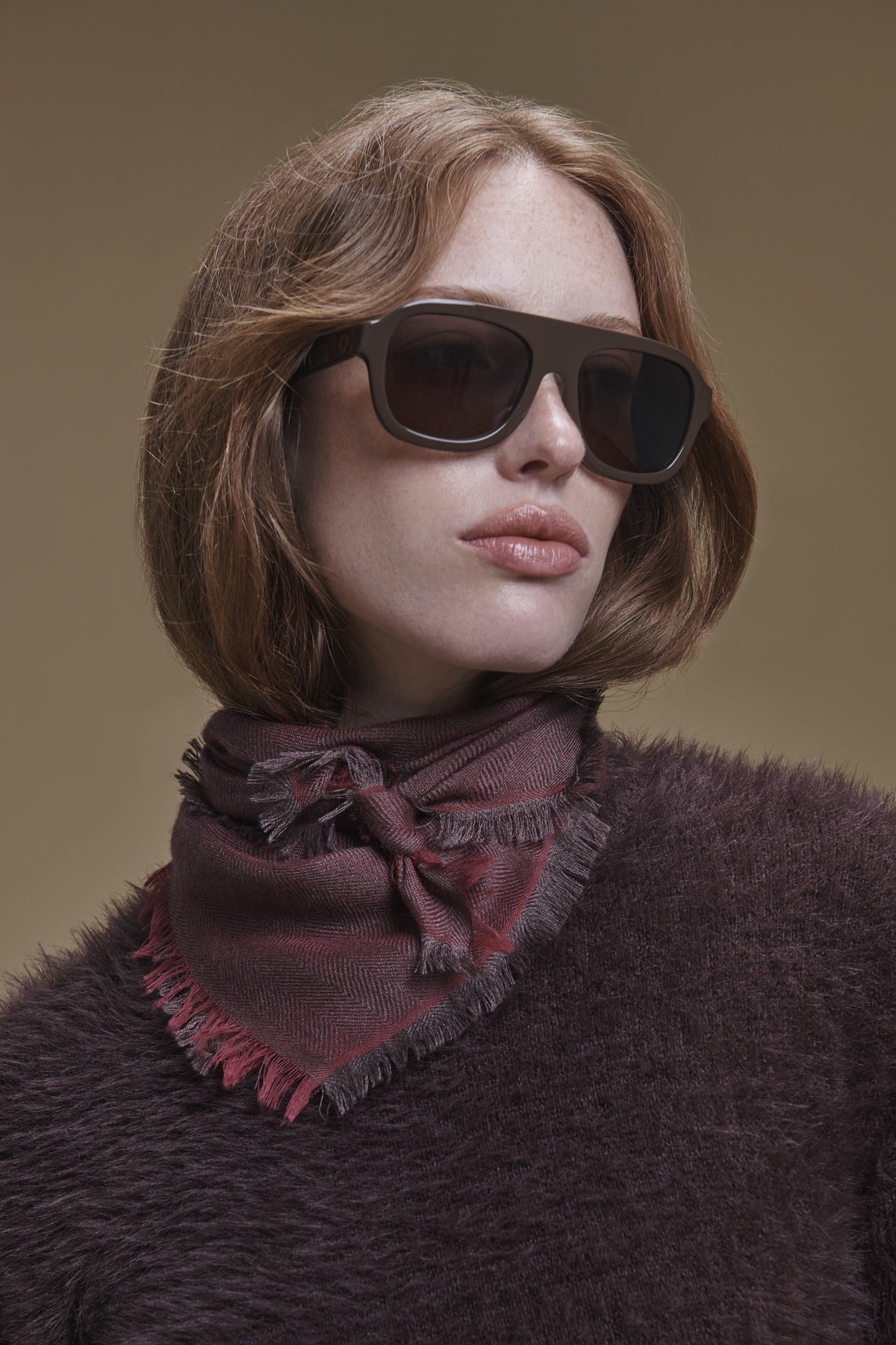 A person wearing sunglasses and a maroon SUMMER CASHMERE HERRINGBONE SCARF tied around their neck.