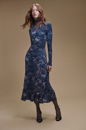 A person wearing a dark blue patterned TAYLOR PRINTED TEE and a matching calf-length skirt in feather jersey.