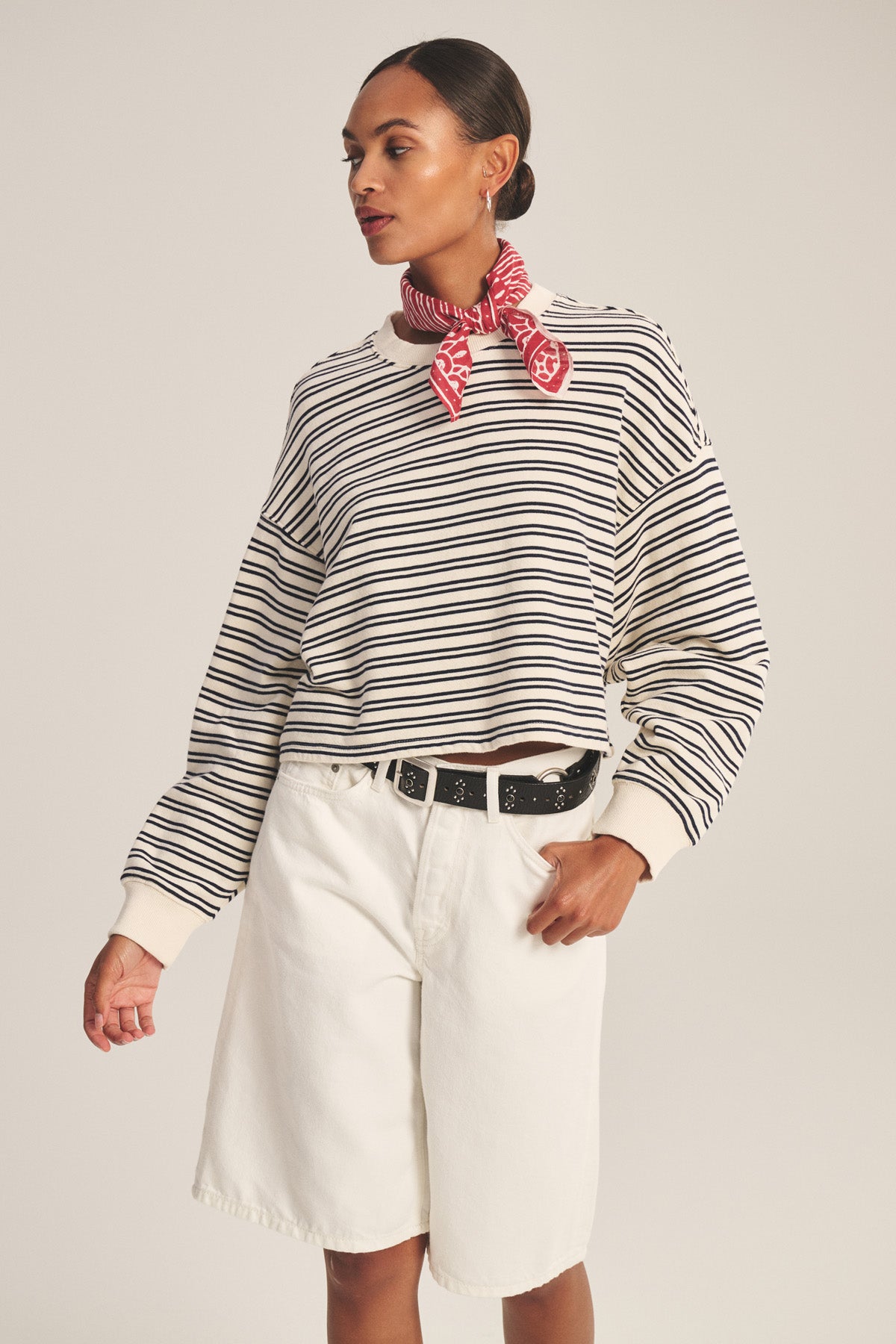 Model wears the ISABELLE PULLOVER by Velvet by Graham & Spencer—black and white stripes—paired with white shorts, black belt, and a red patterned neck scarf, set against a plain background.