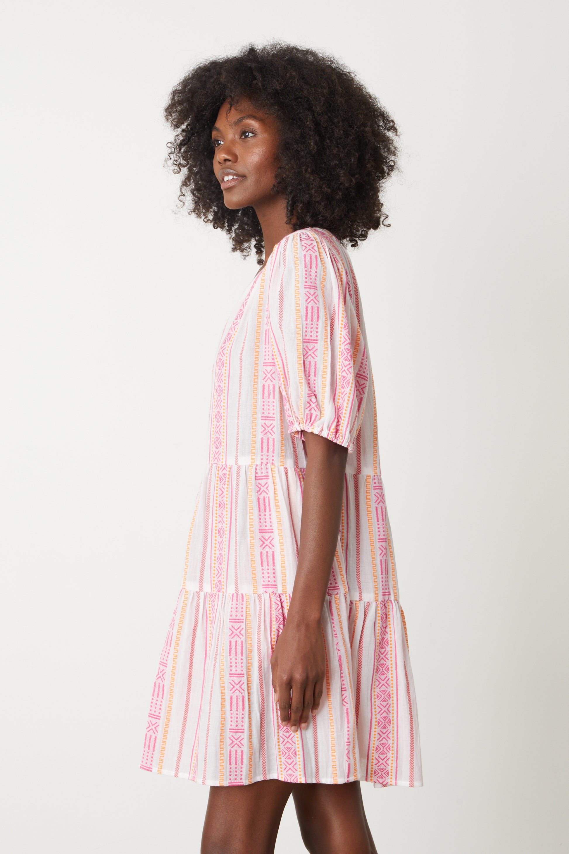   The model is wearing a Velvet by Graham & Spencer MONIQUE JACQUARD BOHO DRESS in pink and white stripe jacquard print 