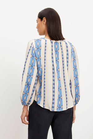 The back view of a woman wearing a Velvet by Graham & Spencer NANNI JACQUARD V-NECK BLOUSE with blue and white stripes.
