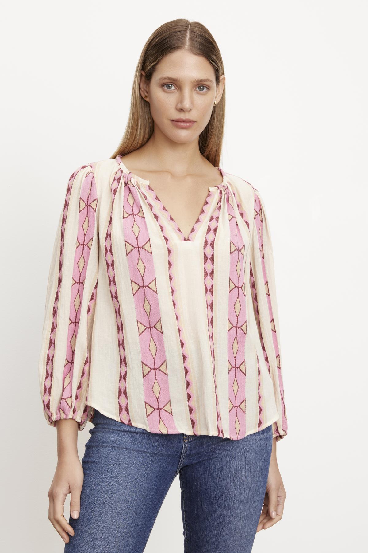   The model is wearing a pink Velvet by Graham & Spencer NANNI JACQUARD V-NECK BLOUSE with elastic cuffs. 
