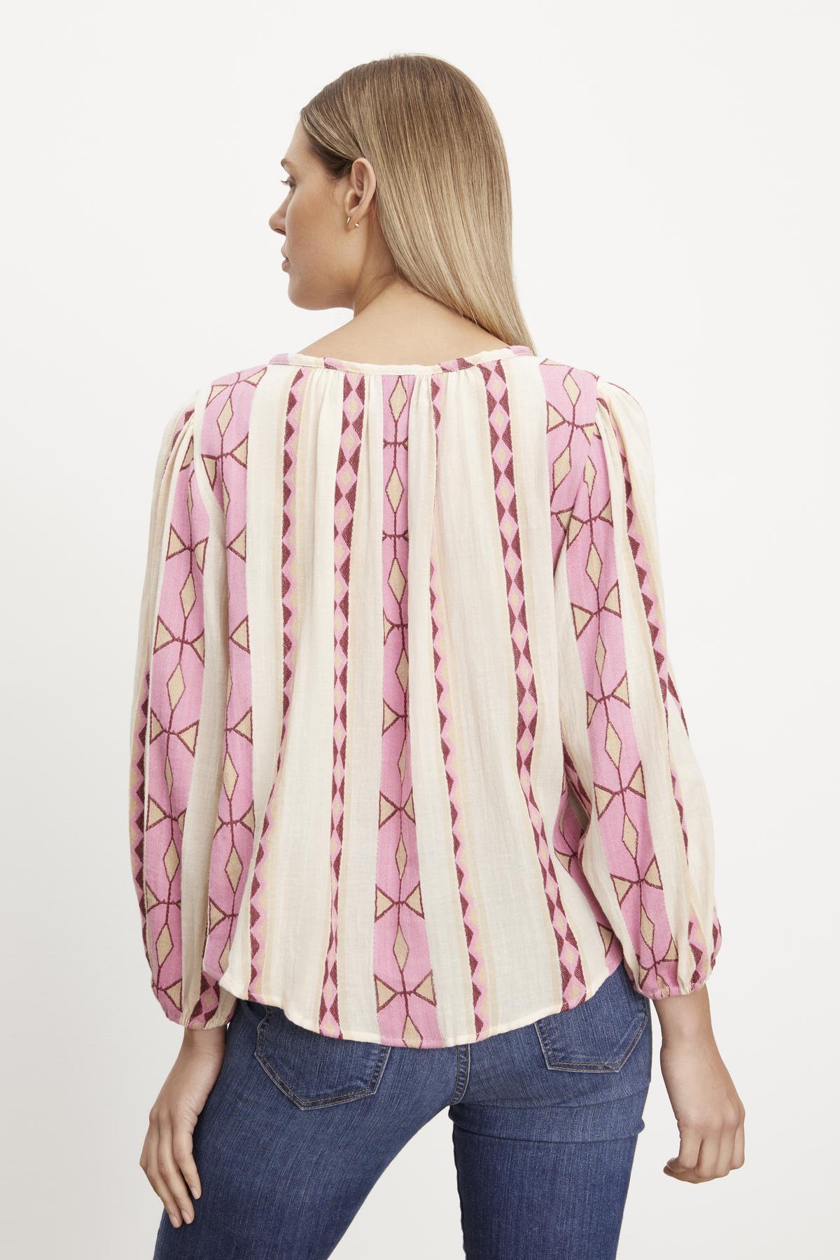   The woman is wearing a pink embroidered blouse with elastic cuffs from Velvet by Graham & Spencer. 