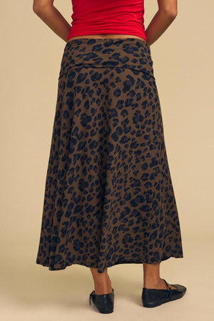 A person is seen from behind wearing a red top paired with the VEDA SKIRT by Velvet by Graham & Spencer, featuring an ankle-length brown and black leopard print design.