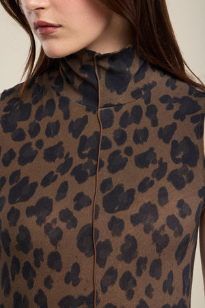 A woman wearing the KELESTINE DRESS by Velvet by Graham & Spencer—a brown, high-neck dress featuring a black leopard print pattern—her face is partially visible, showing neutral lips.