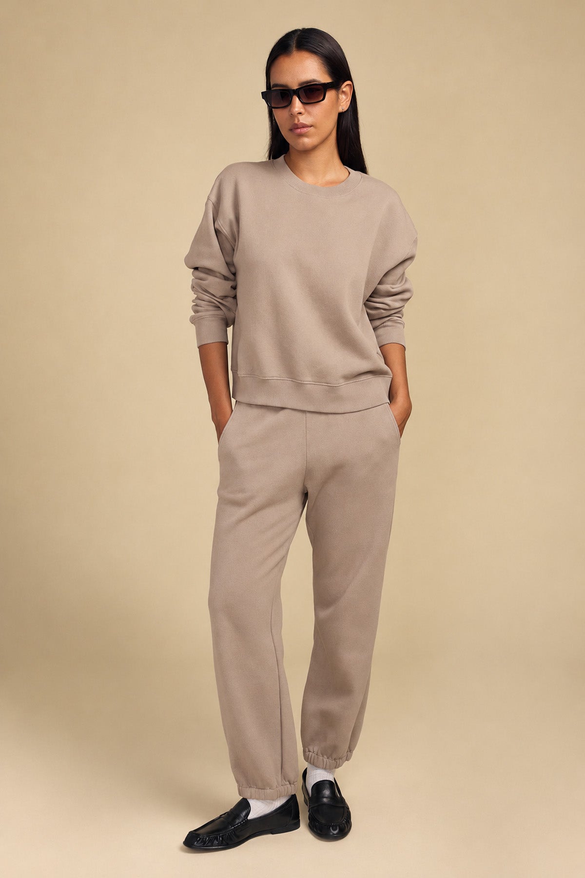 A person wearing a relaxed YOKO SWEATSHIRT and matching sweatpants with black loafers.