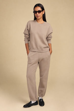 A person wearing a relaxed YOKO SWEATSHIRT and matching sweatpants with black loafers.
