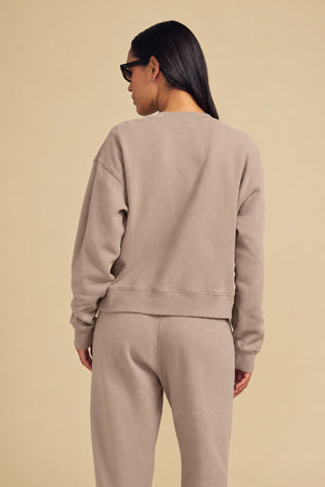 Back view of a person wearing a beige YOKO SWEATSHIRT and matching sweatpants in a relaxed silhouette.