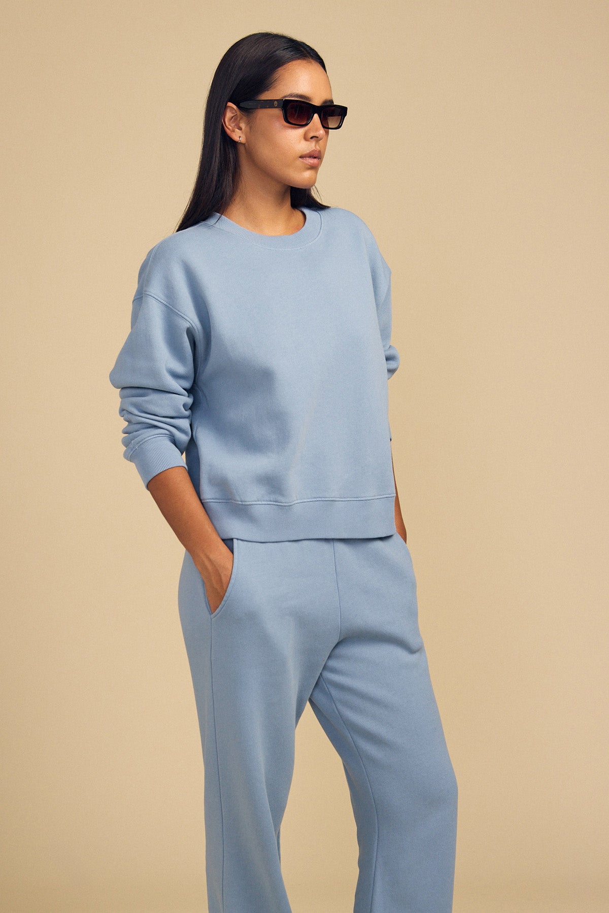 A person in sunglasses wears a matching light blue ZARA SWEATPANT set by Velvet by Graham & Spencer, standing against a plain beige background.