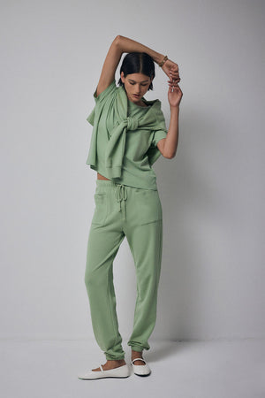 A model wearing a Velvet by Jenny Graham Ynez Sweatshirt in organic cotton green and joggers.