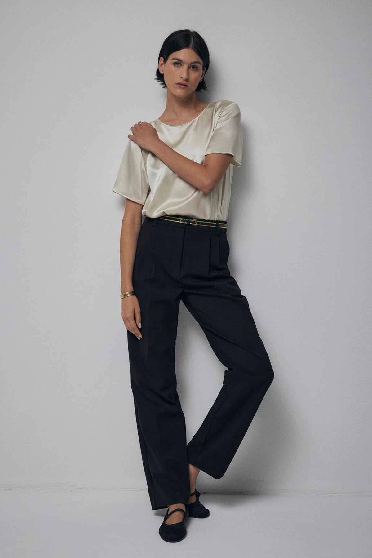   A person standing against a plain background, wearing black trousers, a PASADENA TOP in cream silk charmeuse by Velvet by Jenny Graham, and black flats. 
