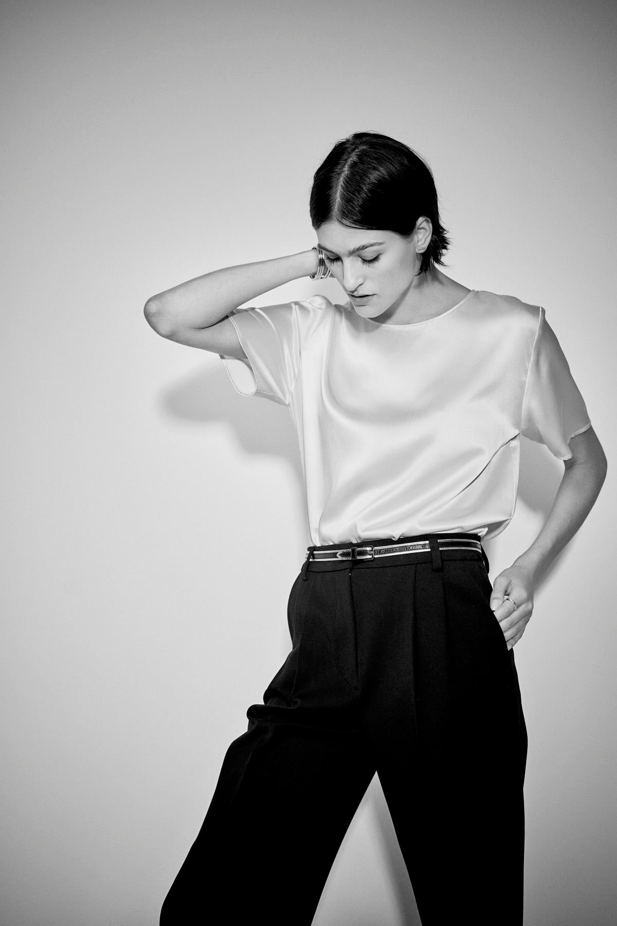   Woman in Velvet by Jenny Graham's PASADENA TOP posing with hand on head against a plain background, radiating timeless elegance. 