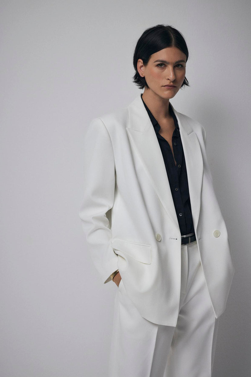 A woman wearing a structured white Fairfax blazer by Velvet by Jenny Graham and black pants.
