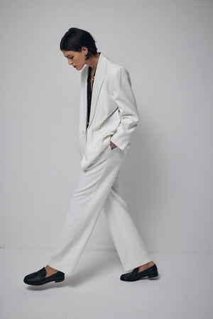 A woman donning a white suit, made of suiting fabric, paired with black shoes.
Product Name: BUNDY PANT
Brand Name: Velvet by Jenny Graham
