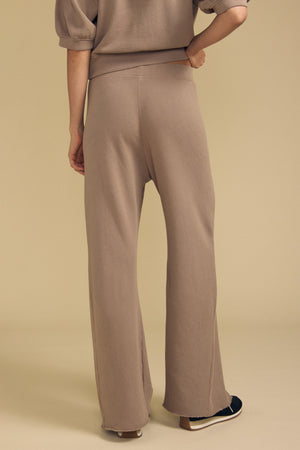 Front view of QHILLA cotton fleece wide leg sweatpant showcasing taupe color and wide-leg fit with a beige background