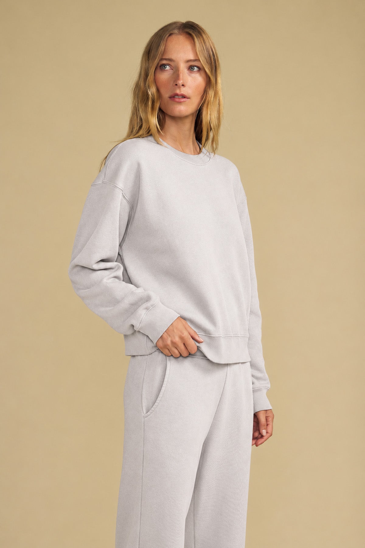 A person wearing a relaxed YOKO SWEATSHIRT and matching lounge pants in light gray cotton fleece.-46320580526273
