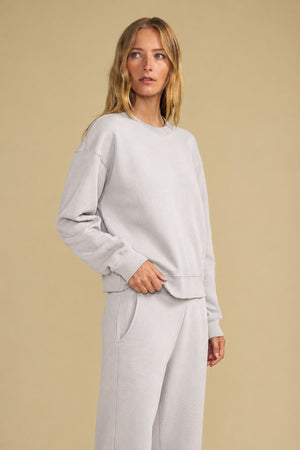 A person wearing a relaxed YOKO SWEATSHIRT and matching lounge pants in light gray cotton fleece.