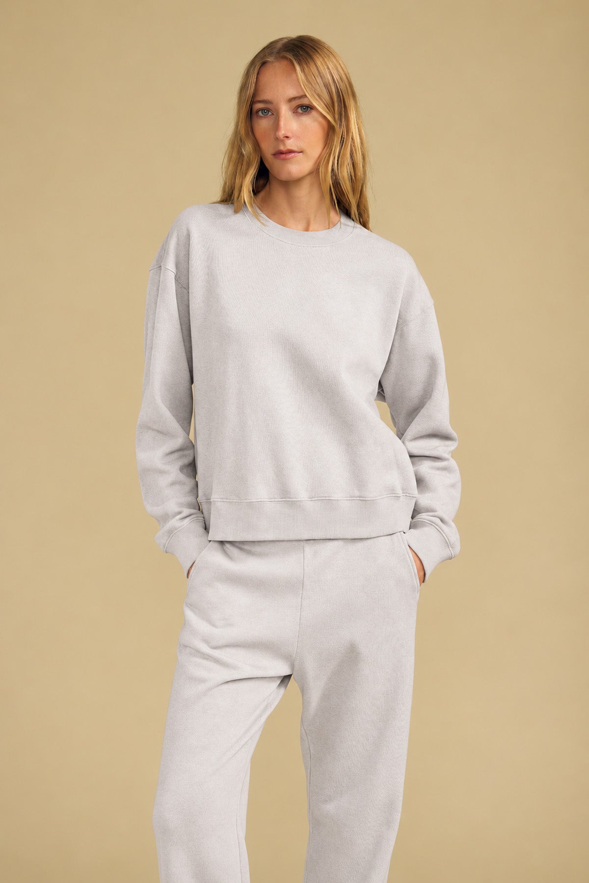 A woman wearing a relaxed YOKO SWEATSHIRT and matching sweatpants with her hands in her pockets.-46320580624577