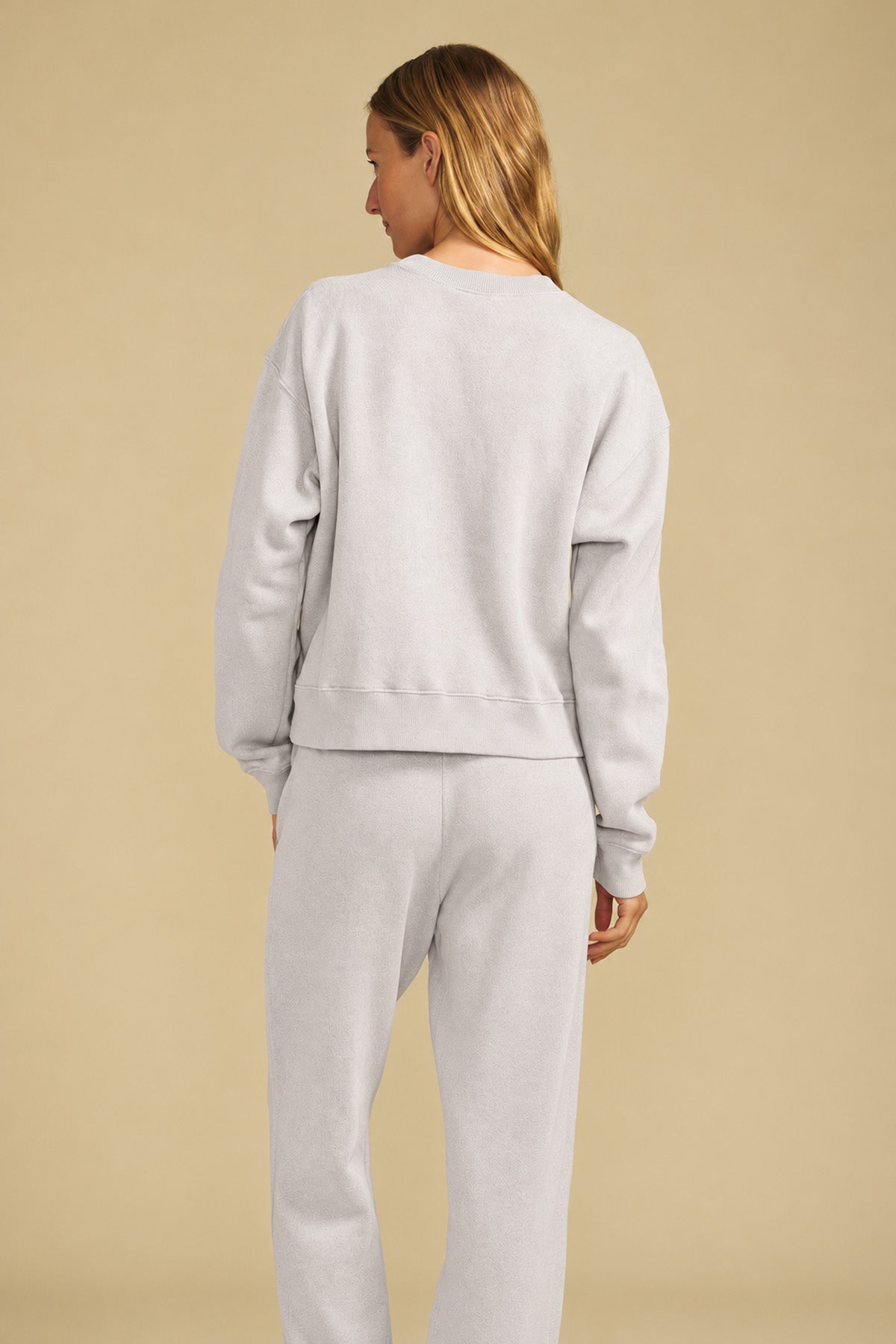 Back view of a person wearing a light gray YOKO SWEATSHIRT and matching cotton fleece sweatpants.