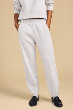 A person wearing a relaxed silhouette light gray YOKO SWEATSHIRT and matching sweatpants with elastic cuffs, paired with black loafers.