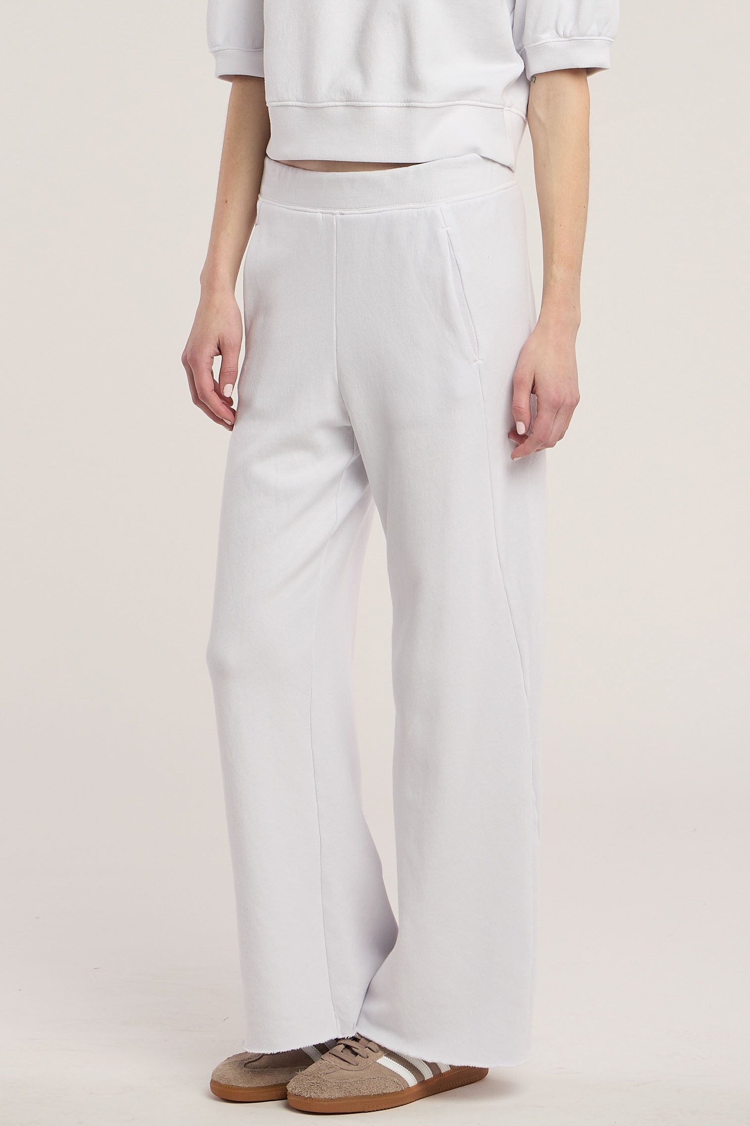 A person wearing the QHILLA SWEATPANT by Velvet by Graham & Spencer, styled with a matching white cropped sweatshirt and brown sneakers, stands against a neutral background.