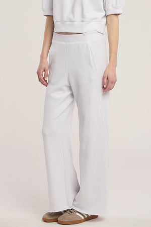 A person wearing the QHILLA SWEATPANT by Velvet by Graham & Spencer, styled with a matching white cropped sweatshirt and brown sneakers, stands against a neutral background.