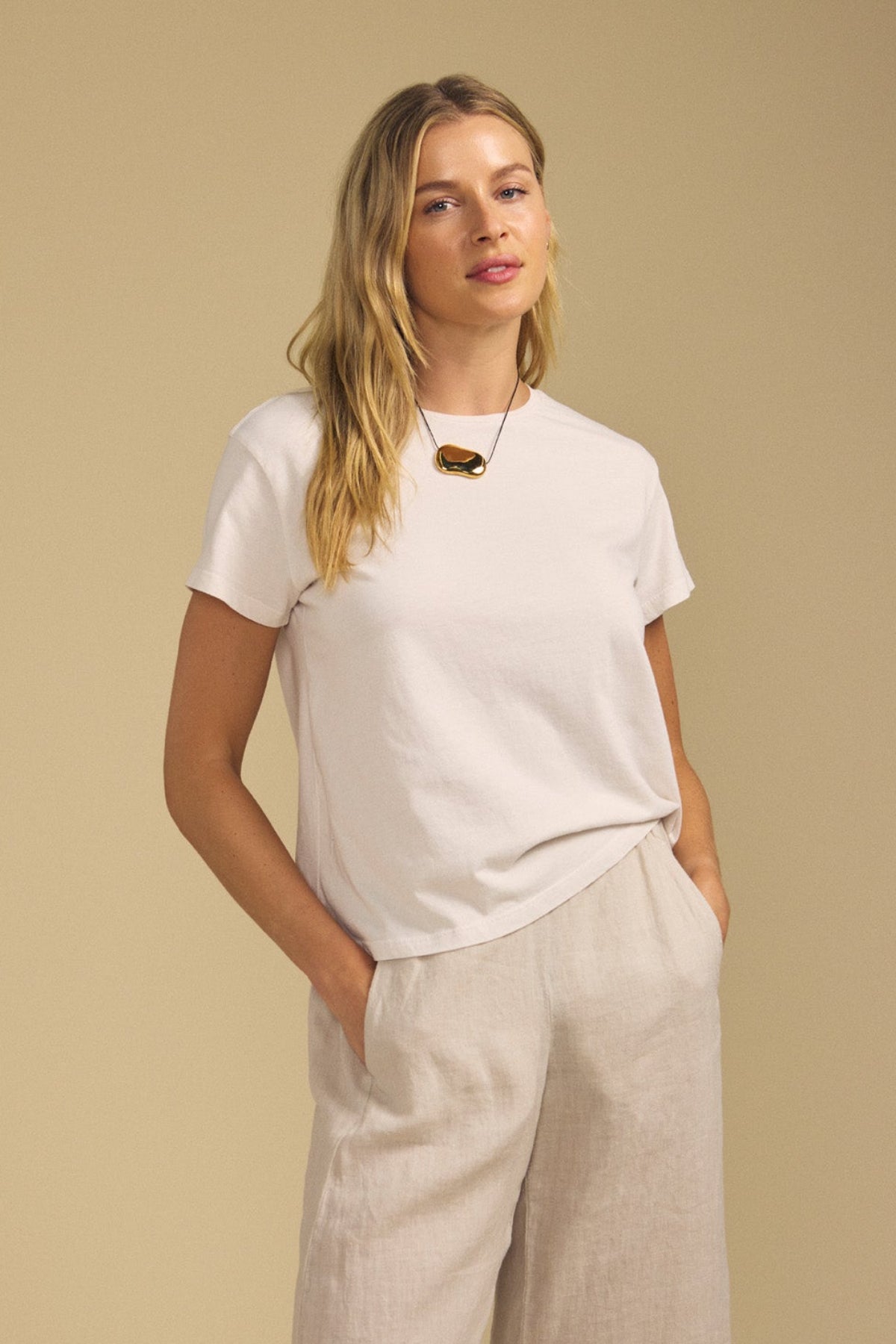 Front view of TIA cotton jersey short sleeve crew neck tee showcasing white short sleeves on model against beige background-41980698329281