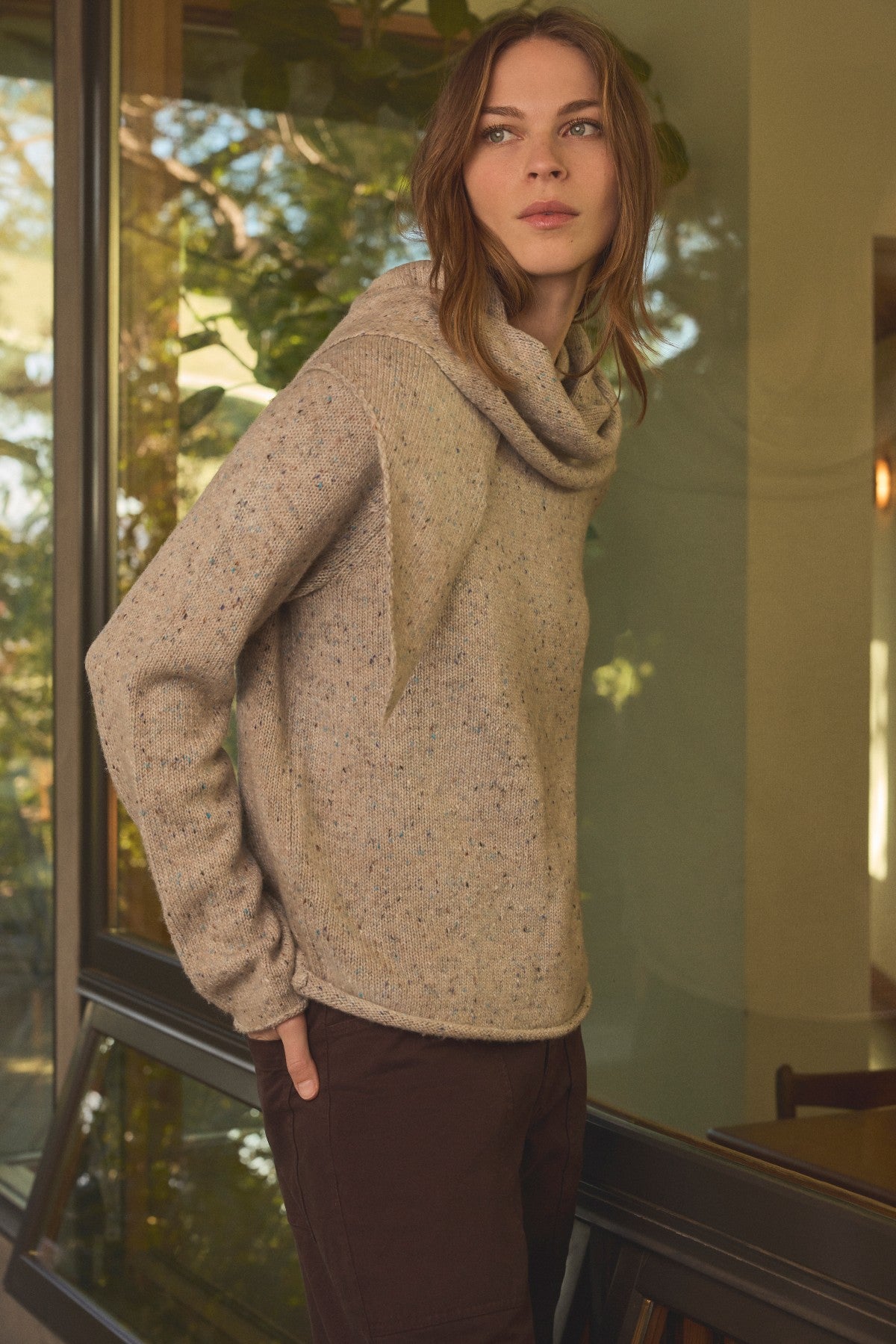 A woman wearing a tan JOELLE SWEATER by Velvet by Graham & Spencer in a tweed knit with a draped cowl neck and an attached scarf detail.