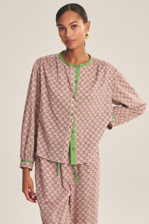 A woman models the KARMEN TOP by Velvet by Graham & Spencer, a relaxed fit button-front pajama top with matching pattern and green trim, set against a simple background.