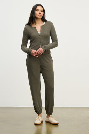 Person standing against a plain background wearing Velvet by Graham & Spencer's LEXIE SWEATPANT in olive green with a relaxed fit and beige sneakers.