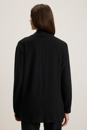 A person with long dark hair is pictured from behind against a plain background, wearing the LISA CARDIGAN by Velvet by Graham & Spencer, featuring an open front and side patch pockets in black triblend knit.