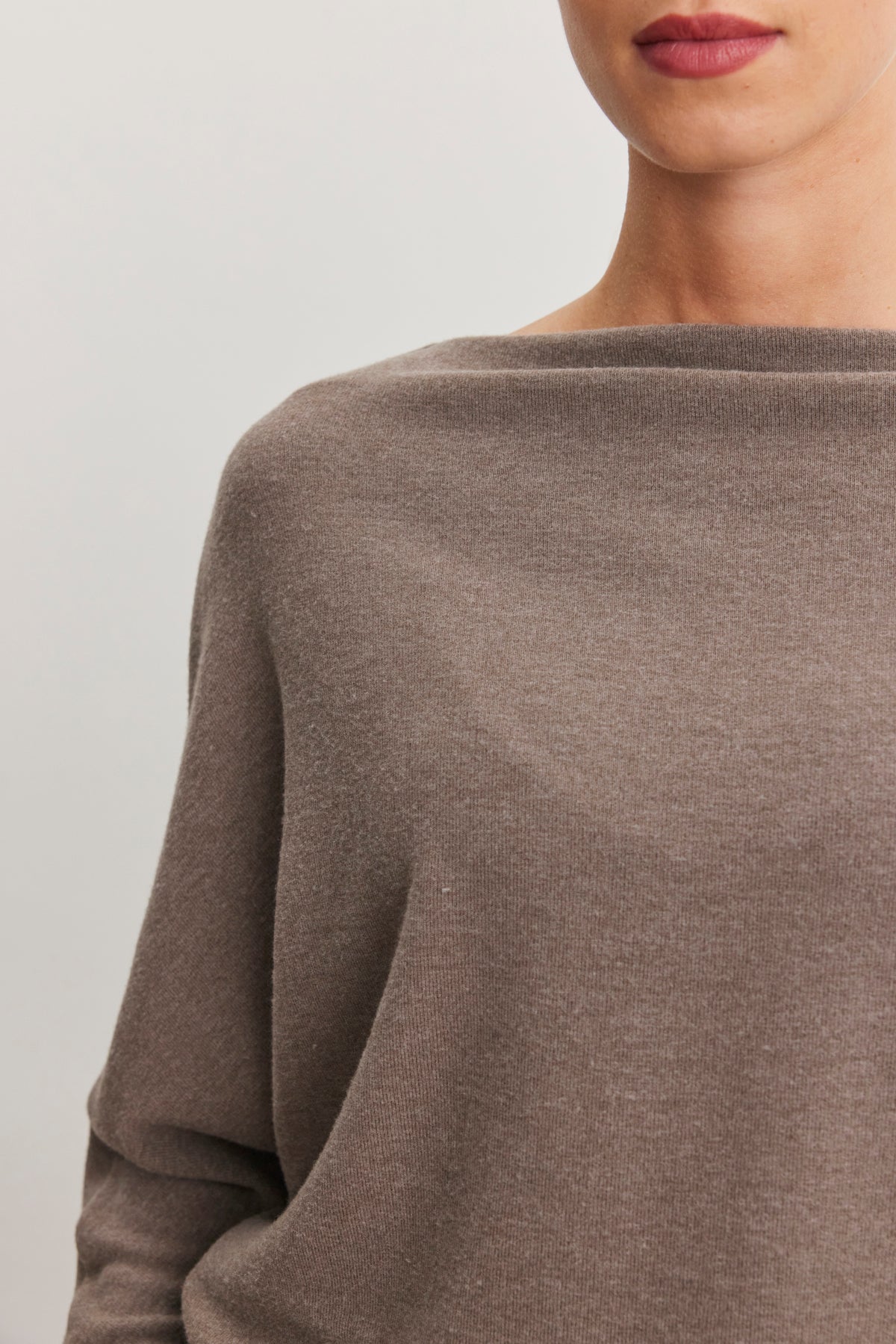   A person is wearing the SELMY TOP in taupe from Velvet by Graham & Spencer, featuring dolman sleeves, visible from nose to waist against a neutral background. 