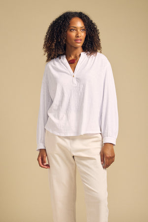 Front view of the white KNOX cotton slub three-quarter-sleeve split-neck tee on a model with cream pants against a beige background