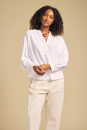 Front view of white KNOX cotton slub 3/4 sleeve split neck tee showcasing relaxed fit on model with beige background