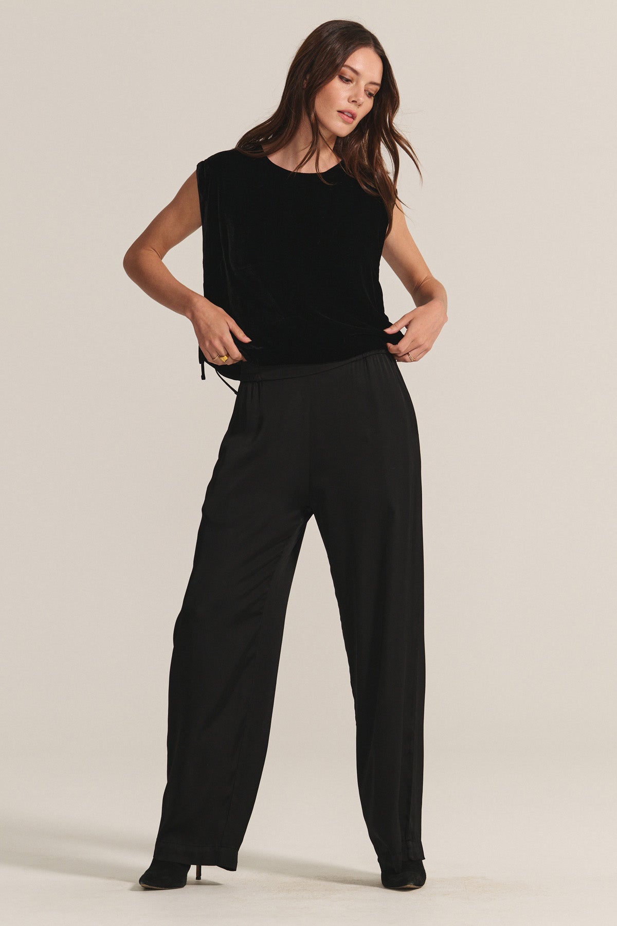   A woman wears the HADLEY TOP by Velvet by Graham & Spencer—a sleeveless, boxy fit silk velvet blouse—paired with loose black pants against a light background, creating an elegant look for any special occasion. 
