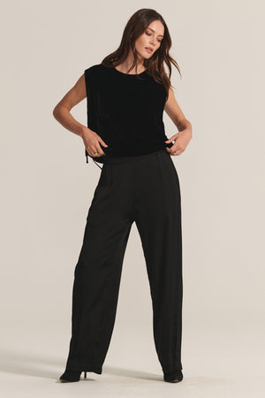 A woman wears the HADLEY TOP by Velvet by Graham & Spencer—a sleeveless, boxy fit silk velvet blouse—paired with loose black pants against a light background, creating an elegant look for any special occasion.