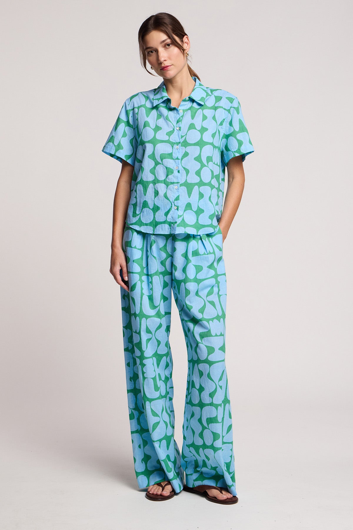 A woman wears the Velvet by Graham & Spencer MARINE SHIRT in light blue and green Lido print cotton cambric with matching wide-leg pants, standing against a plain background.