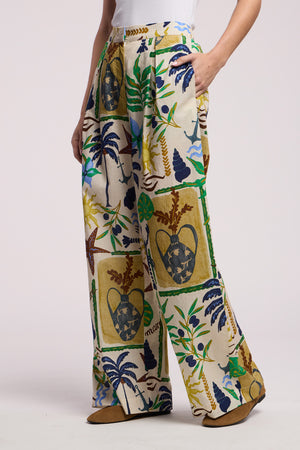 Model wears the TRIXIE PANT by Velvet by Graham & Spencer, featuring a wide-leg silhouette with vibrant tropical and marine life patterns, styled with a white top and brown shoes.