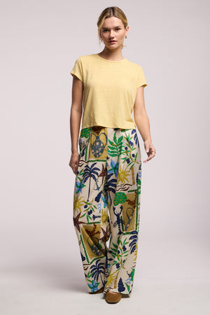 A woman wears the Velvet by Graham & Spencer TRIXIE PANT, vibrant cotton cambric with a wide leg silhouette, paired with a short-sleeved yellow top, standing against a plain light background.