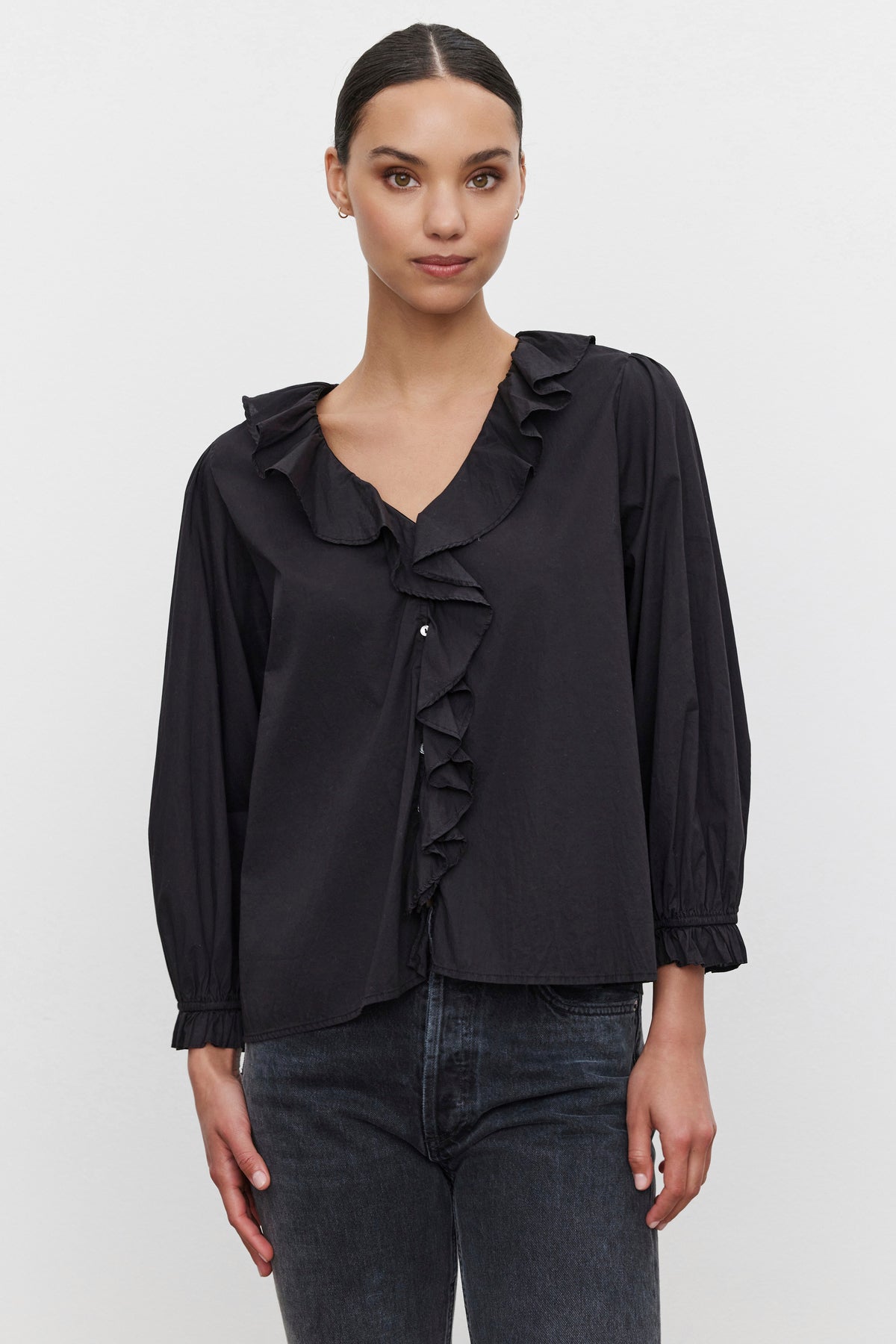   A person wearing the CINTHIA BLOUSE by Velvet by Graham & Spencer paired with dark jeans, standing against a plain background. 