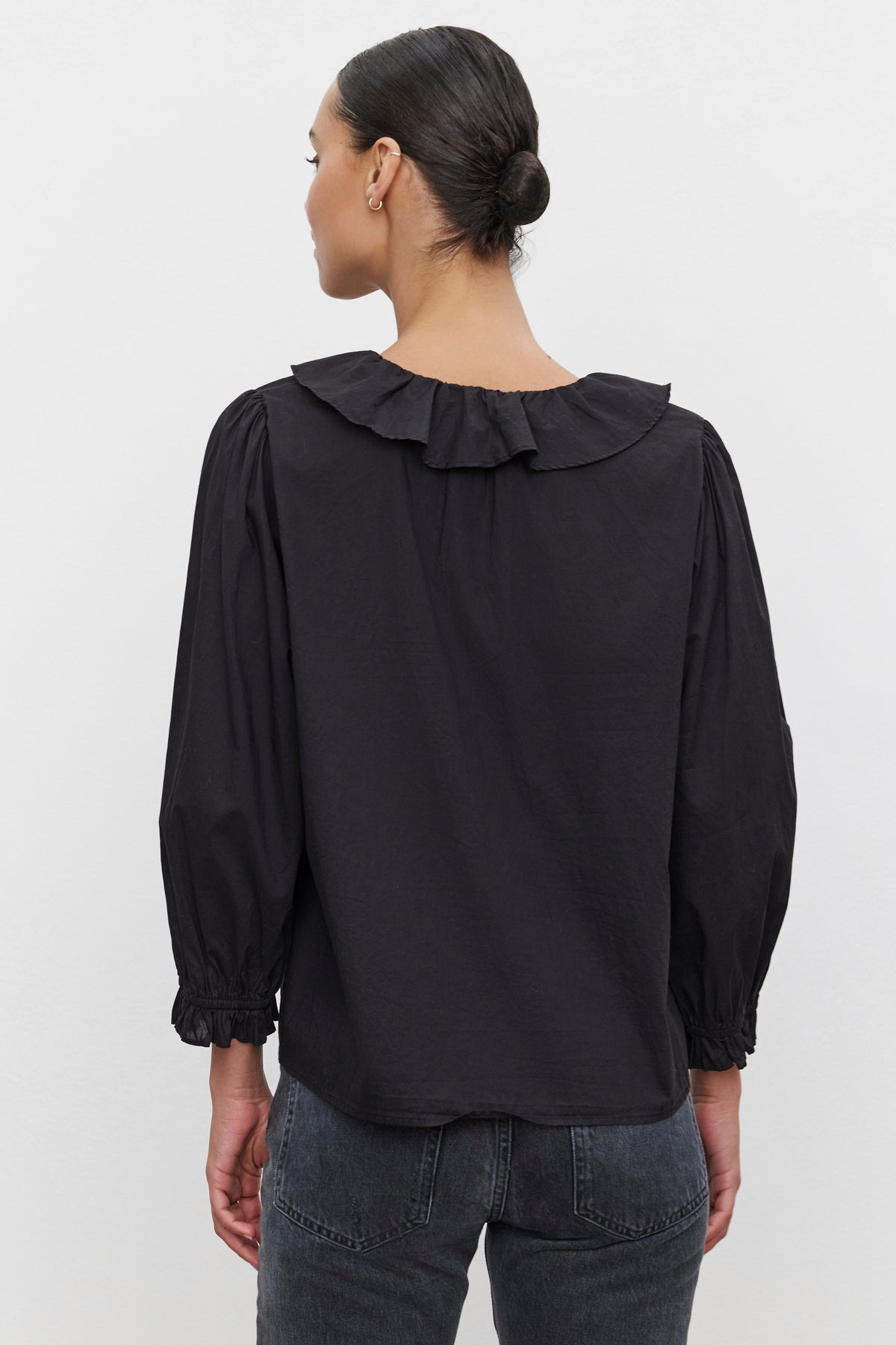   A person is seen from behind wearing the CINTHIA BLOUSE from Velvet by Graham & Spencer, featuring puffed sleeves and a ruffled collar. 