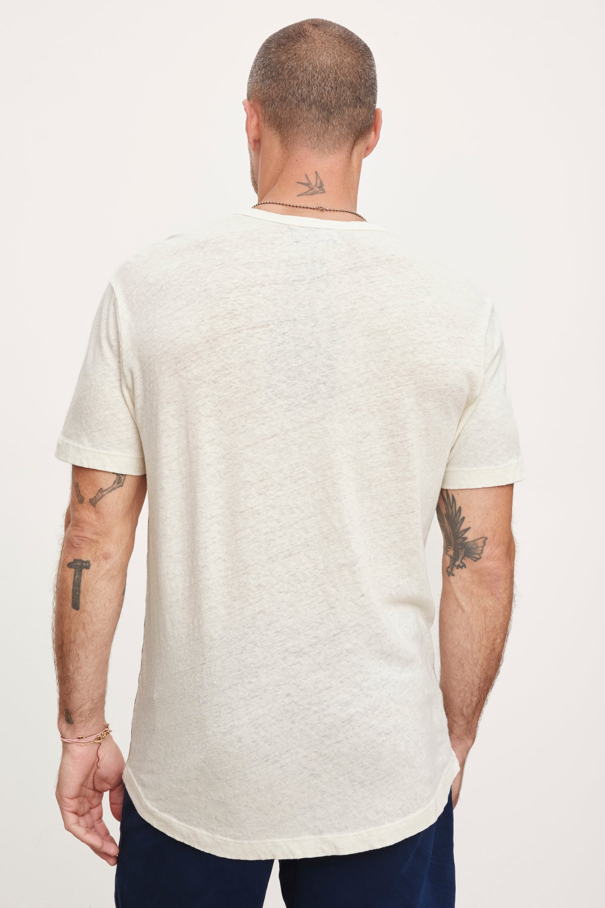 Rear view of a man wearing a Velvet by Graham & Spencer DAVEY TEE showing tattoos on his arms and neck.-36732521316545