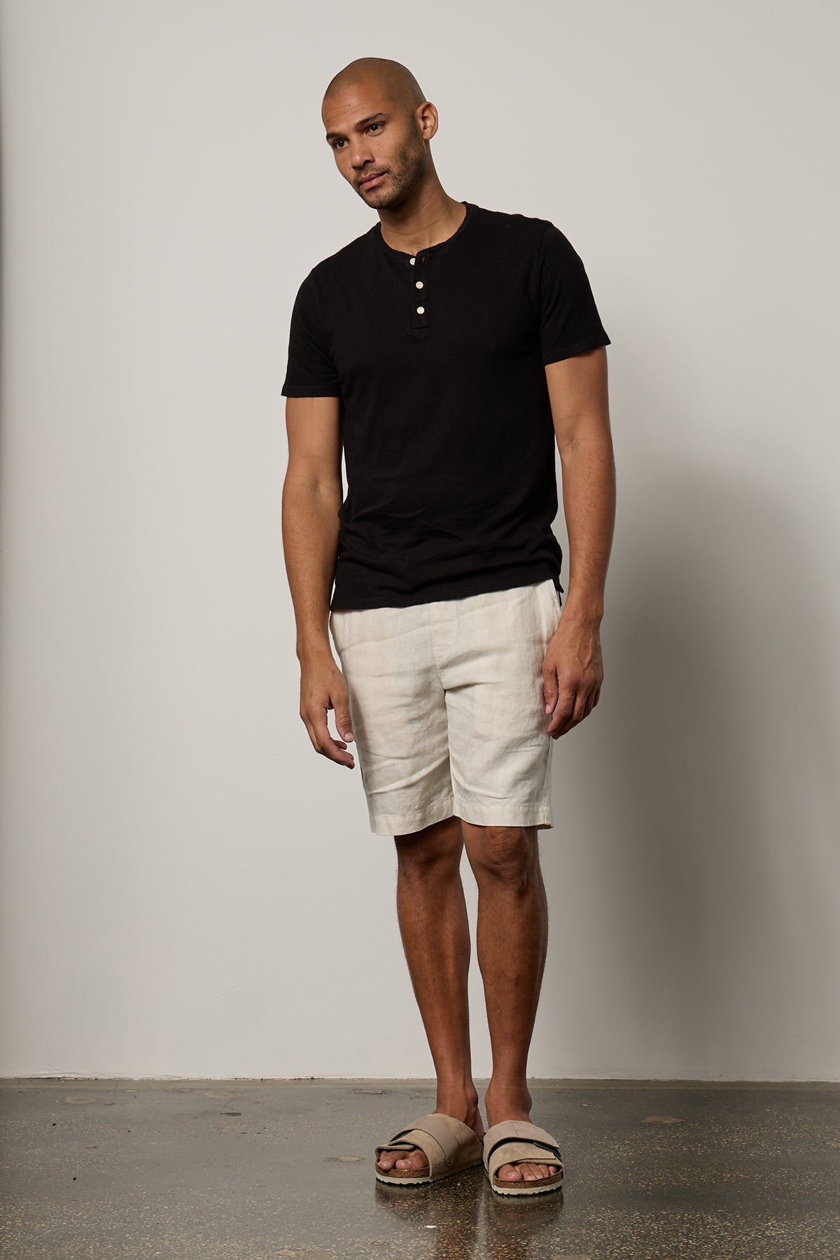   Man wearing Lionel Henley in black full length front with Jonathan linen shorts in beach full length front with Birkenstocks 