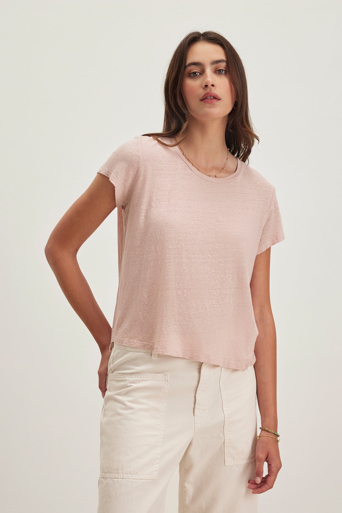 A person wearing a Velvet by Graham & Spencer CASEY LINEN KNIT TEE in light pink and off-white pants stands against a plain background.-38662914769089