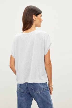 The back view of a woman wearing raw edge detailing jeans and a Velvet by Graham & Spencer HUDSON CREW NECK TEE.