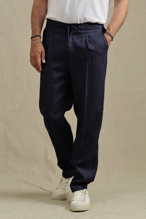 A person wearing the ELLIOTT PANT by Velvet by Graham & Spencer, a white t-shirt, and white sneakers stands against a neutral background.