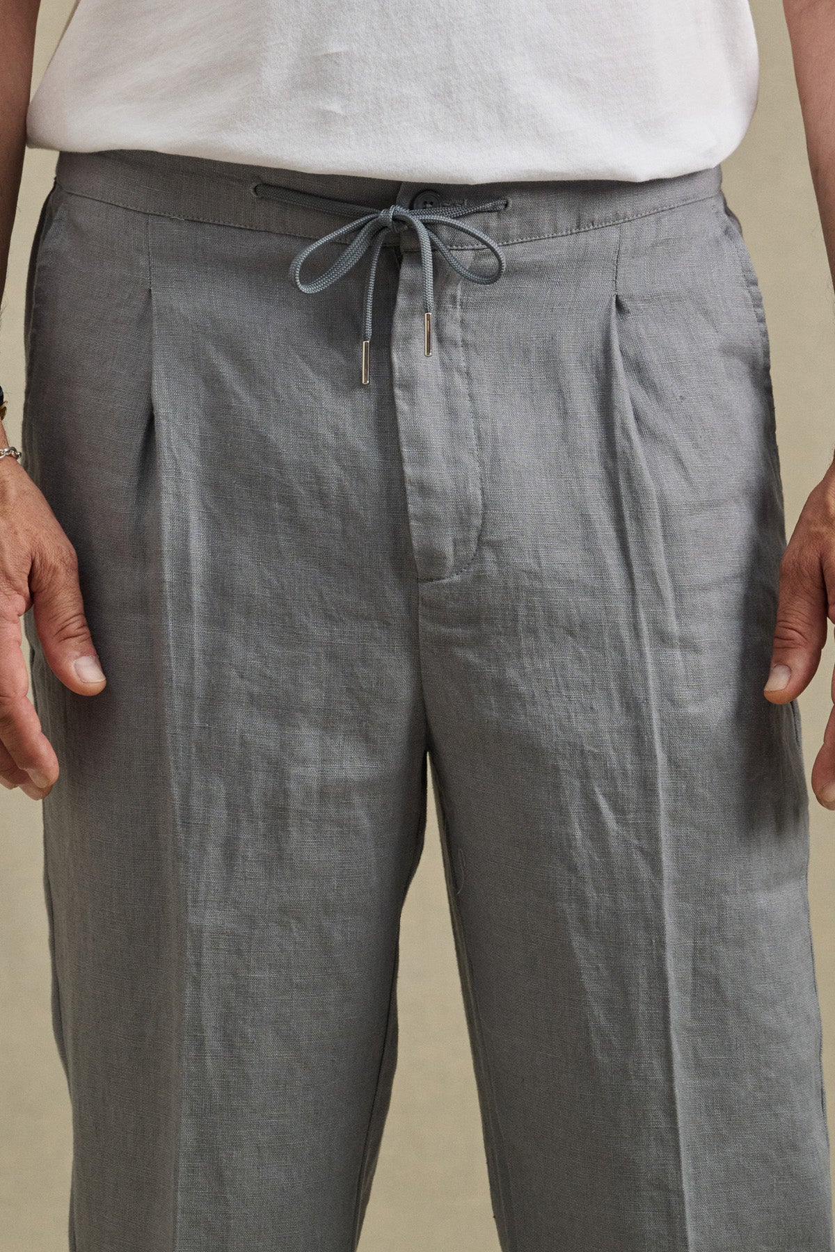 A person shown from waist to mid-thigh wearing the ELLIOTT PANT by Velvet by Graham & Spencer in light gray slim-fit linen, paired with a white shirt.-41479915765953