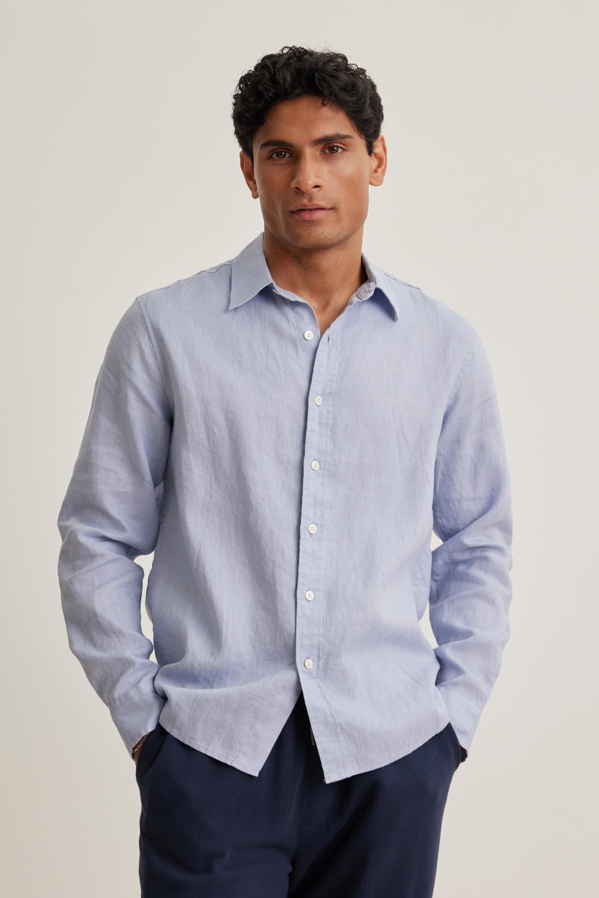   A person wearing a CARUSO LINEN BUTTON-UP SHIRT by Velvet by Graham & Spencer and dark pants stands against a plain background. 