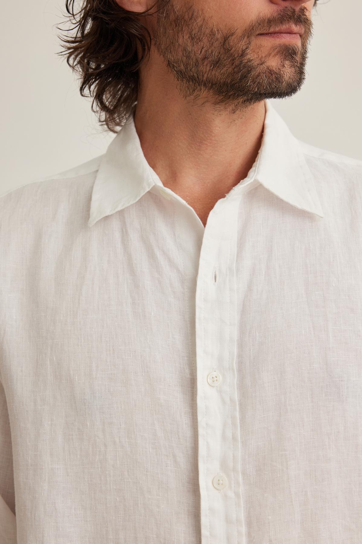   A person wearing a CARUSO LINEN BUTTON-UP SHIRT by Velvet by Graham & Spencer featuring an open collar, highlighting the shirt and upper body. 